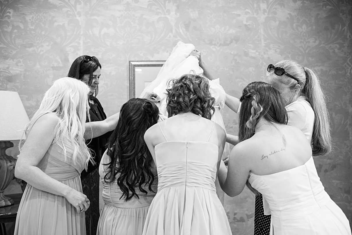bridesmaids helping bride get dressed