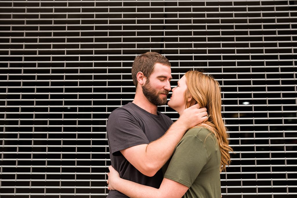 couple giving eskimo kisses in front of grate door