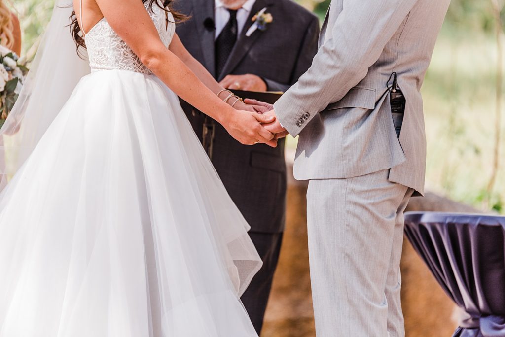 bride and groom holding hands during ceremony