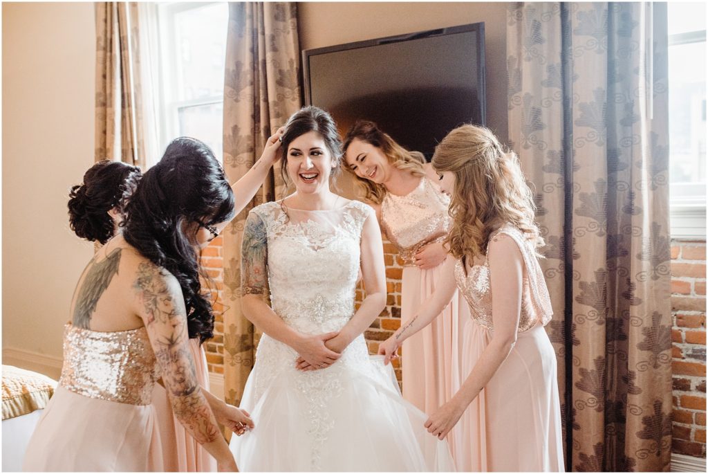 bridesmaids helping bride get dressed