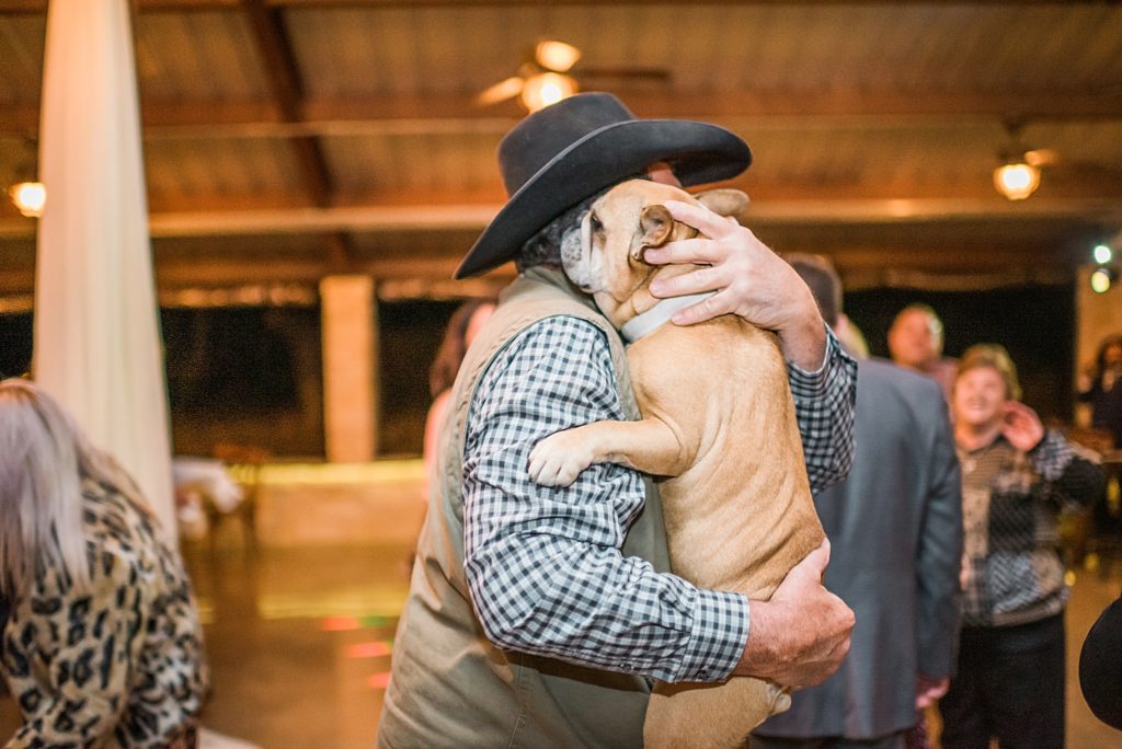 man dancing with dog at wedding reception
