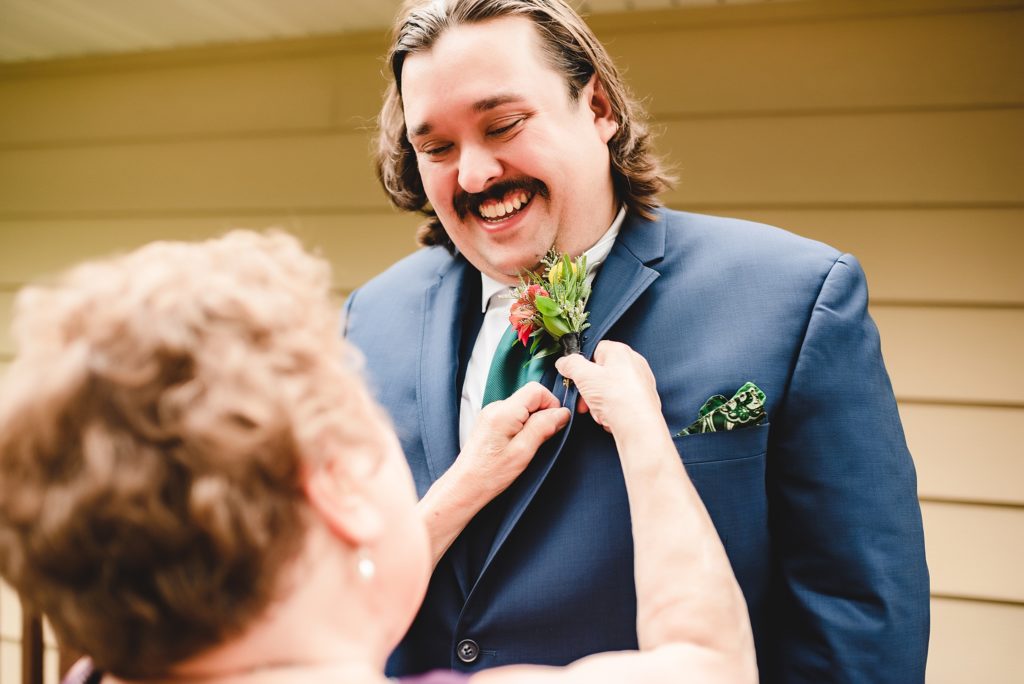 groom and mother putting on boutonnieres 