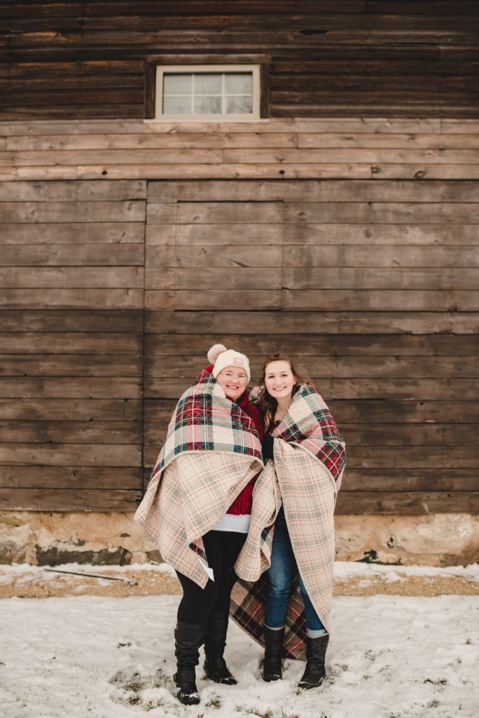 sisters wrapped in plaid quilt for christmasy family session