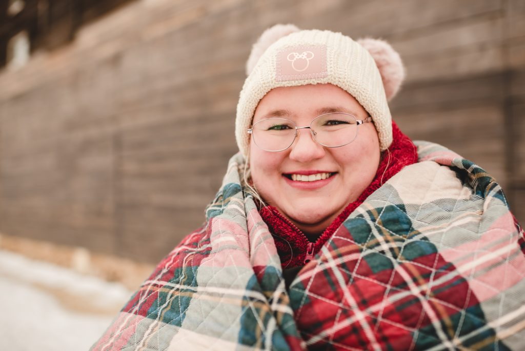 woman smiling wrapped in plaid quilt