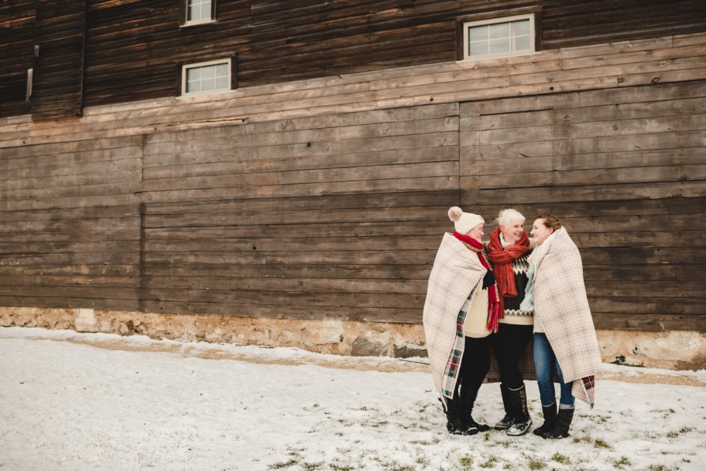 mom and daughers wrapped in plaid quilt for winter photo session
