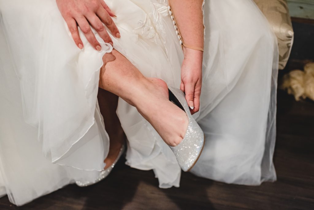 bride putting on silver flats