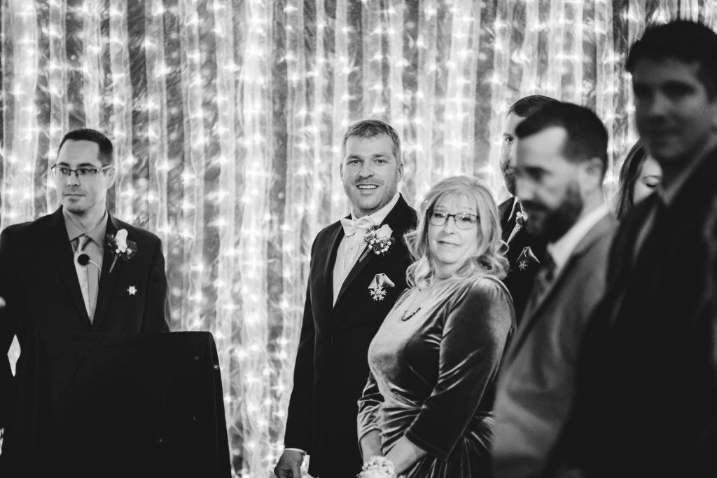 black and white photo of groom looking down the aisle at wedding ceremony