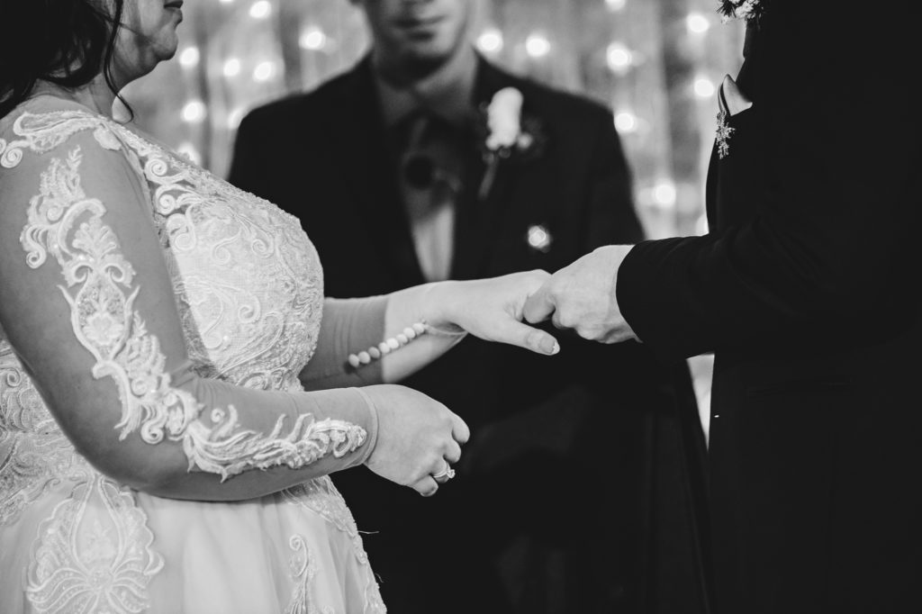 black and white image of groom putting ring on bride's finger