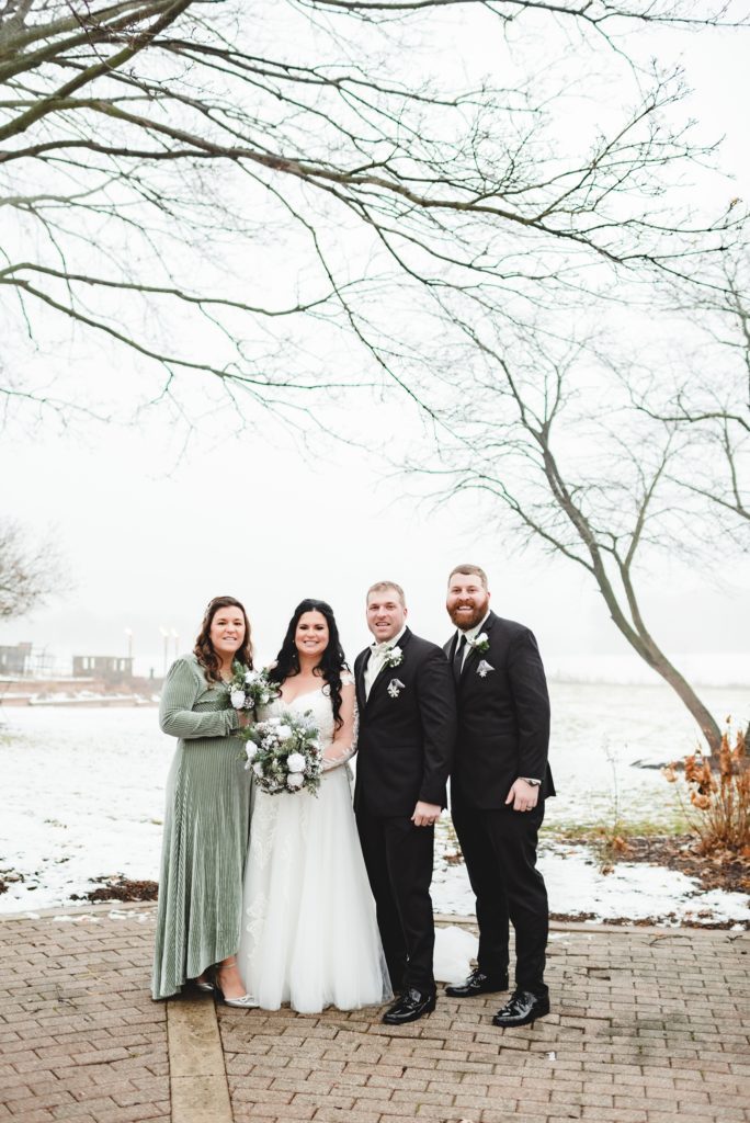 winter wedding party with formal tuxes and sage green dresses