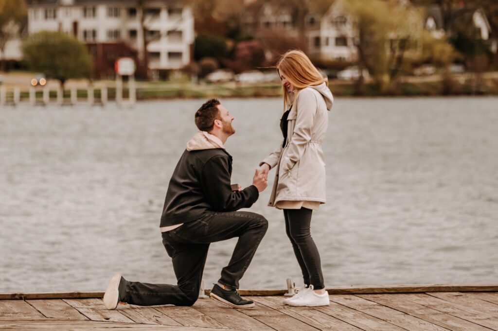 man proposing to woman on a lake boat dock