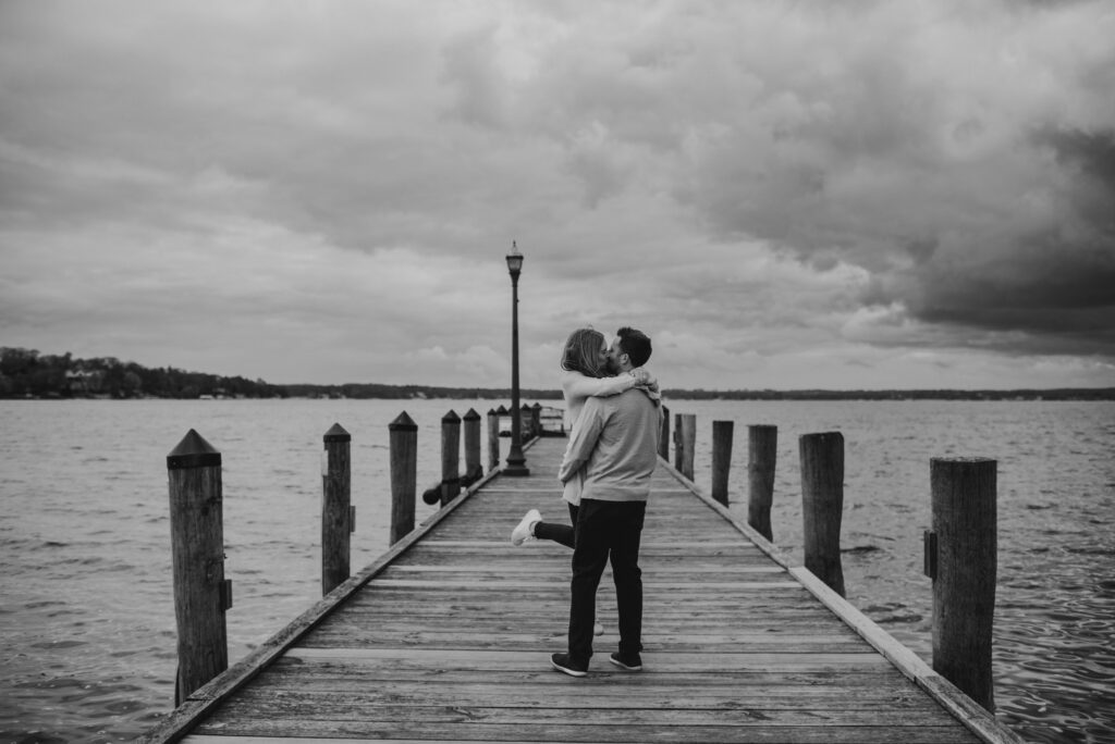 black and white photo of couple kissing and spinning on a stormy day