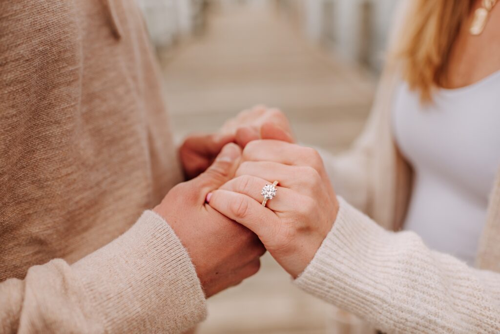 man and woman holding hands showcasing engagement ring