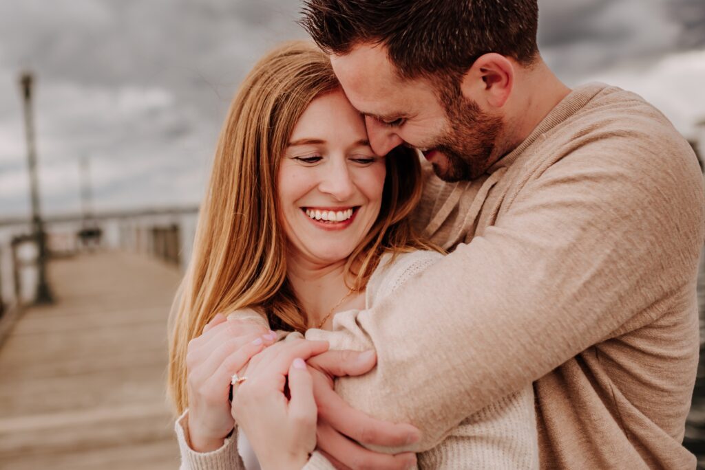 man and woman snuggling in together for an engagement photo