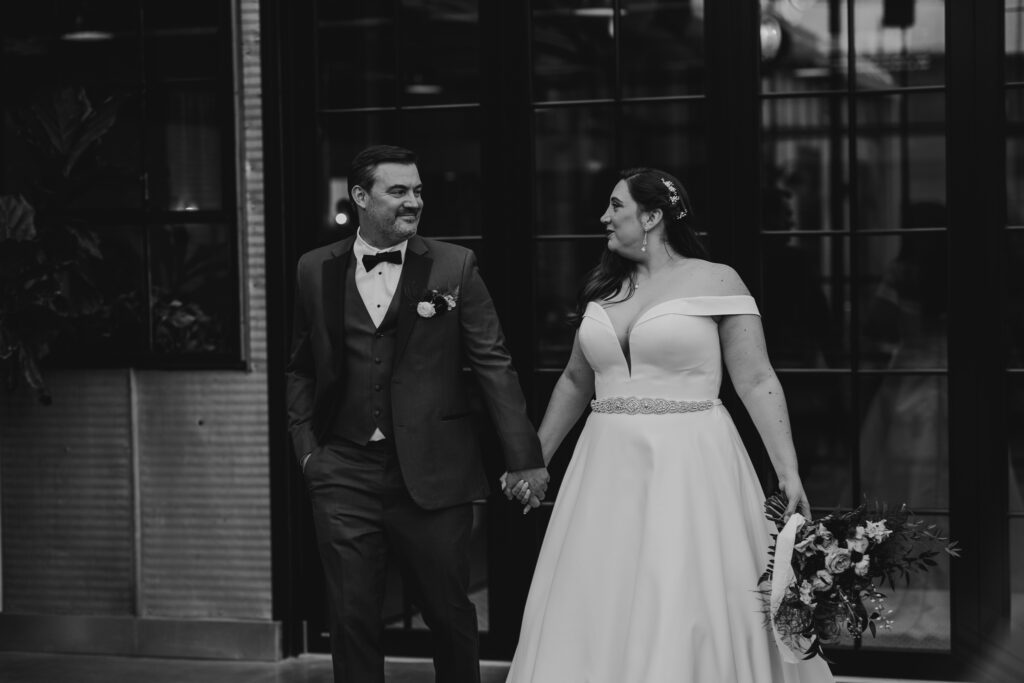 black and white photo of bride and groom walking together