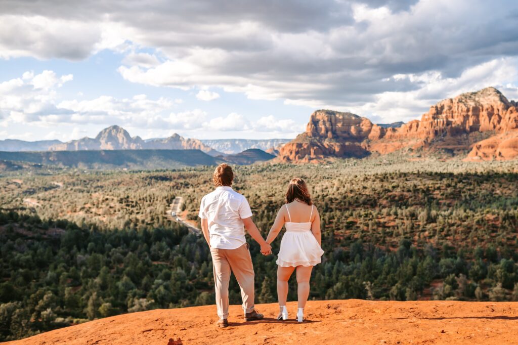 couple holding hands looking out at sedona landscape