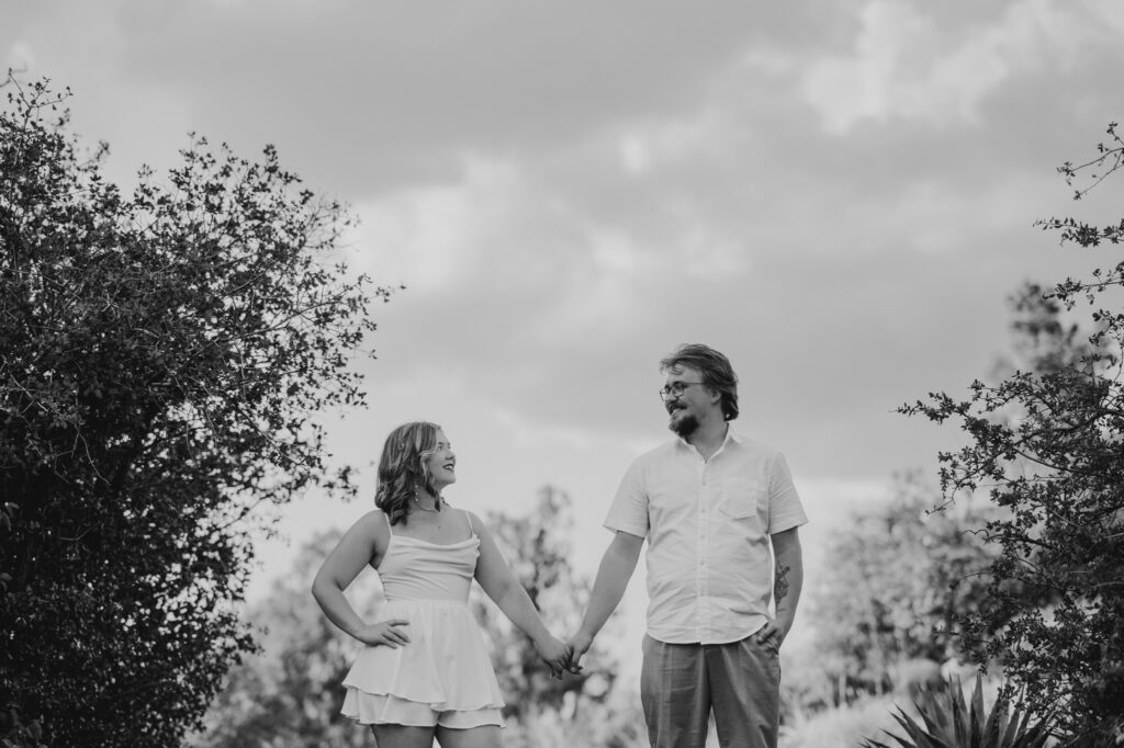 black and white photo of couple holding hands in the center and looking at each other