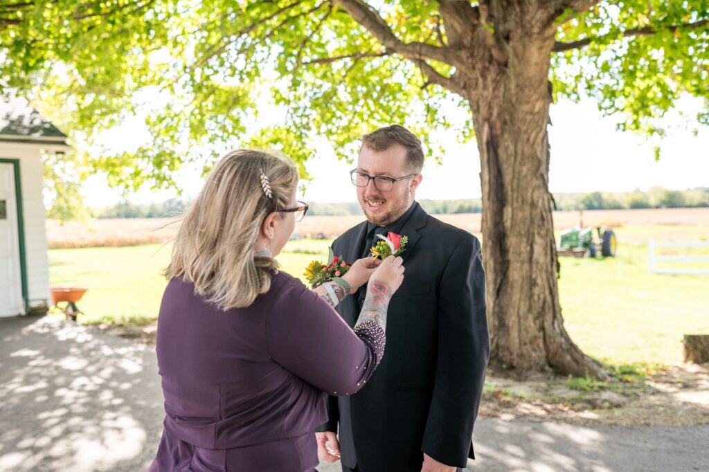 mother of the groom putting on his boutonniere 