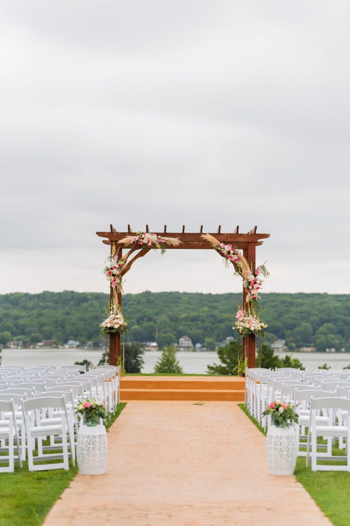 outdoor wedding ceremony with a wood pergola and flowers overlooking a golf course