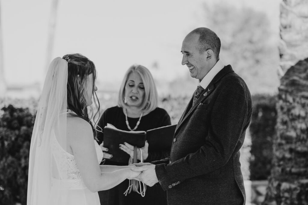 bride and groom holding hands with officiant in the background
