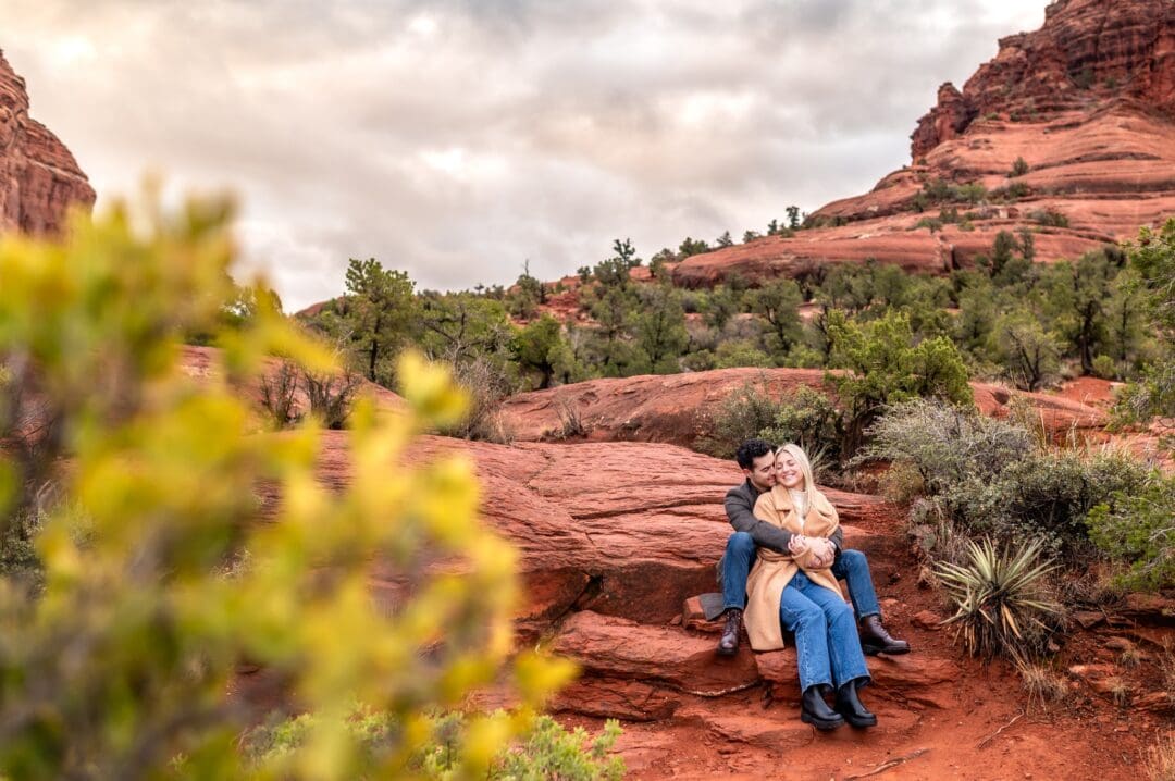 man and woman sitting together romantically on red rocks in sedona