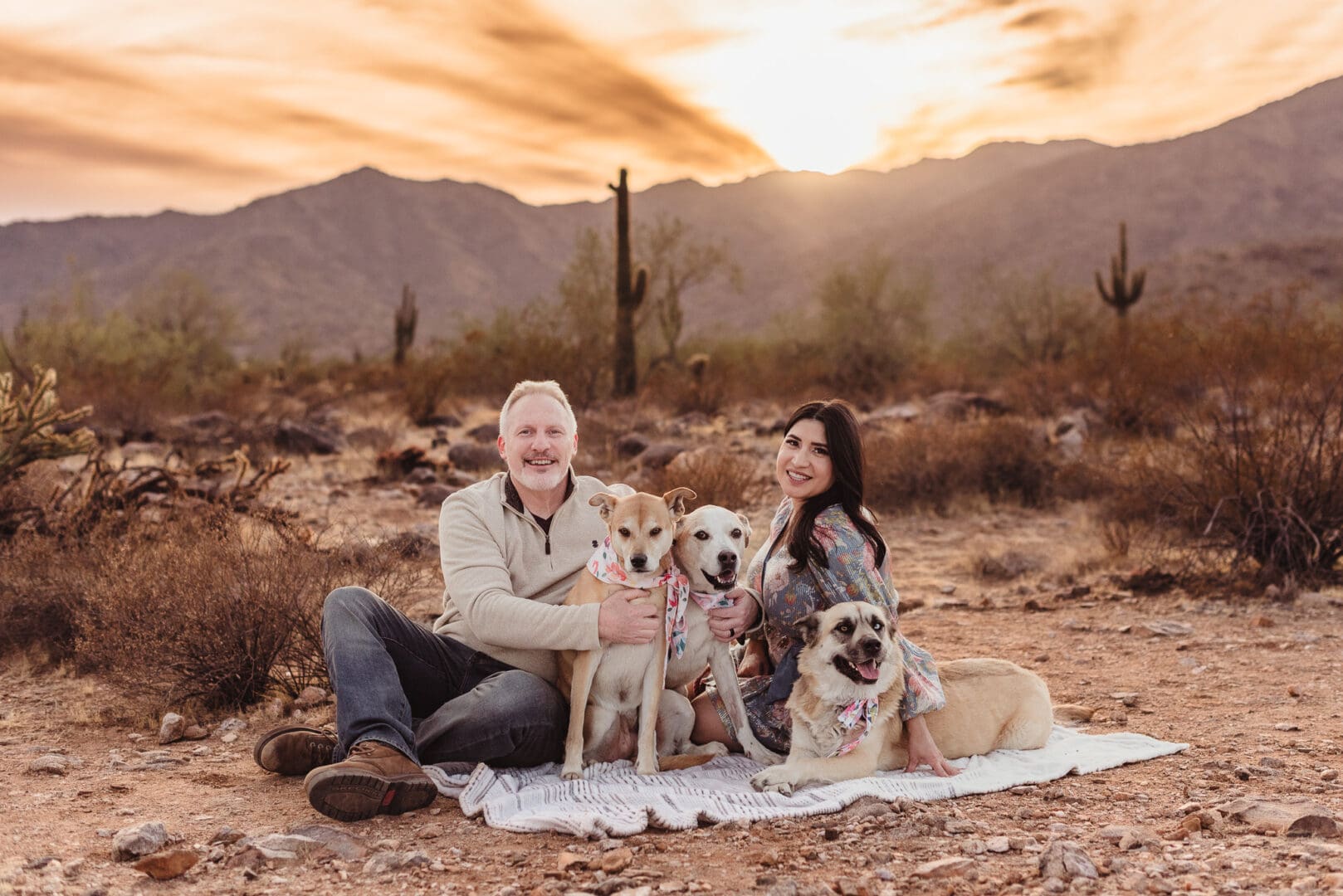 couple with their 3 dogs on a blanket in the desert
