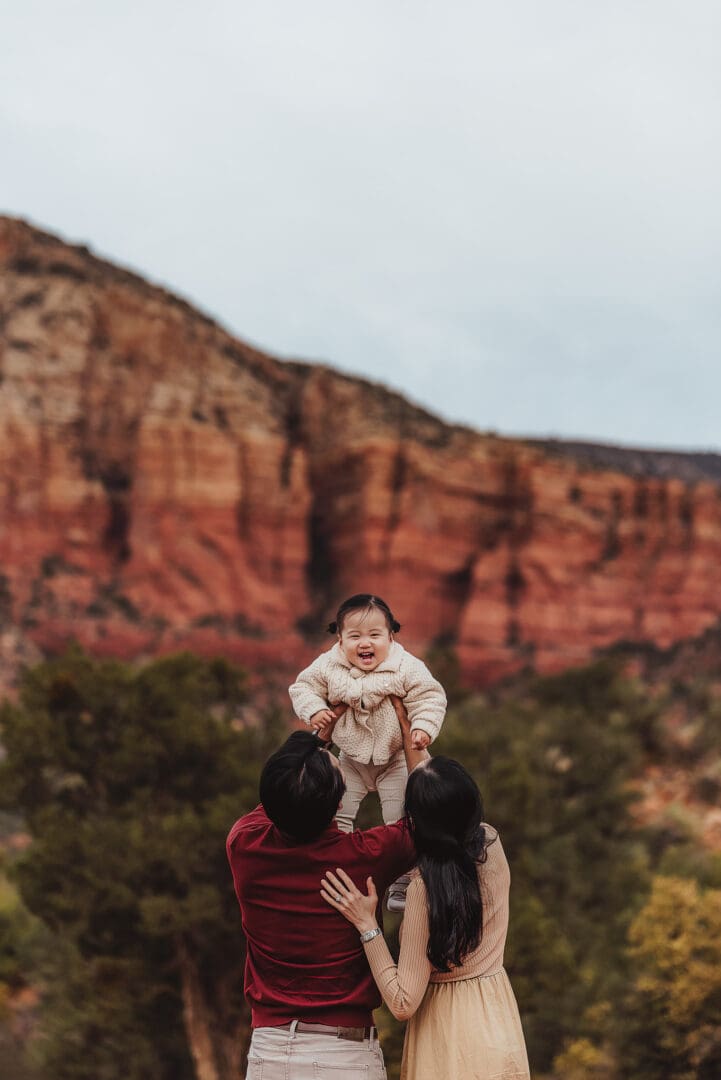 parents lifting toddler with a big smile