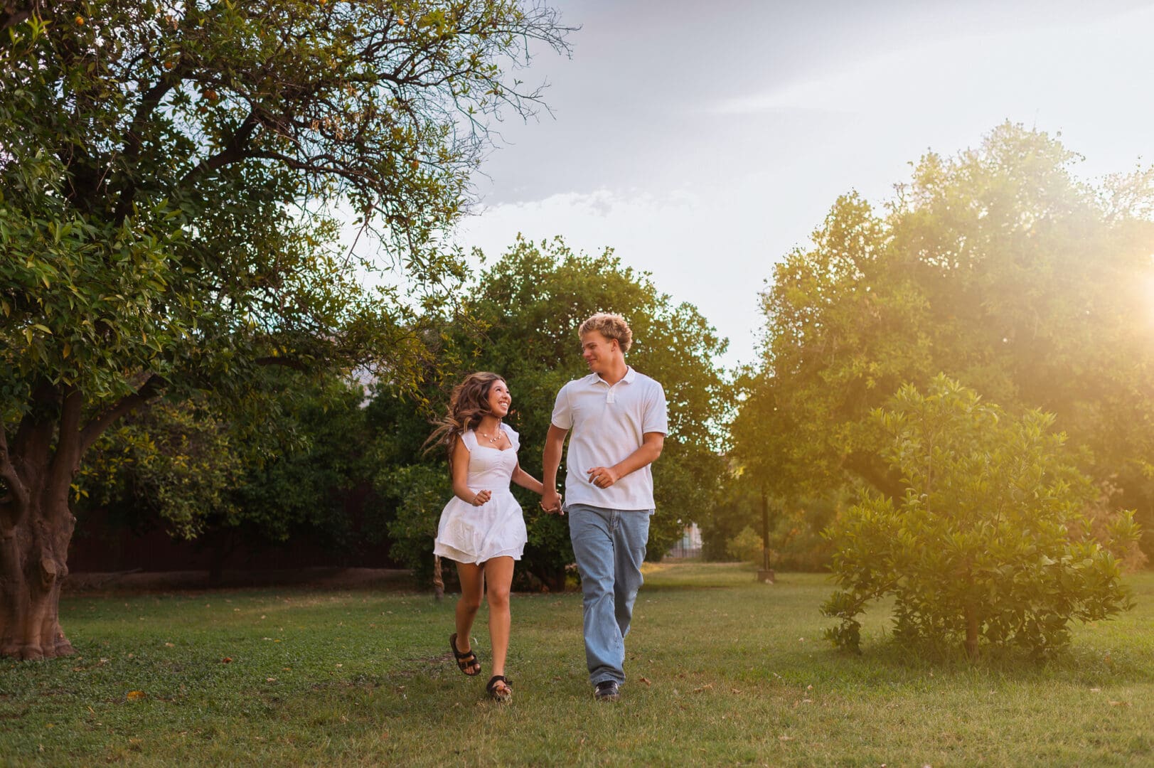 young teenage couple running together through an orchard at manistee ranch in glendale arizona