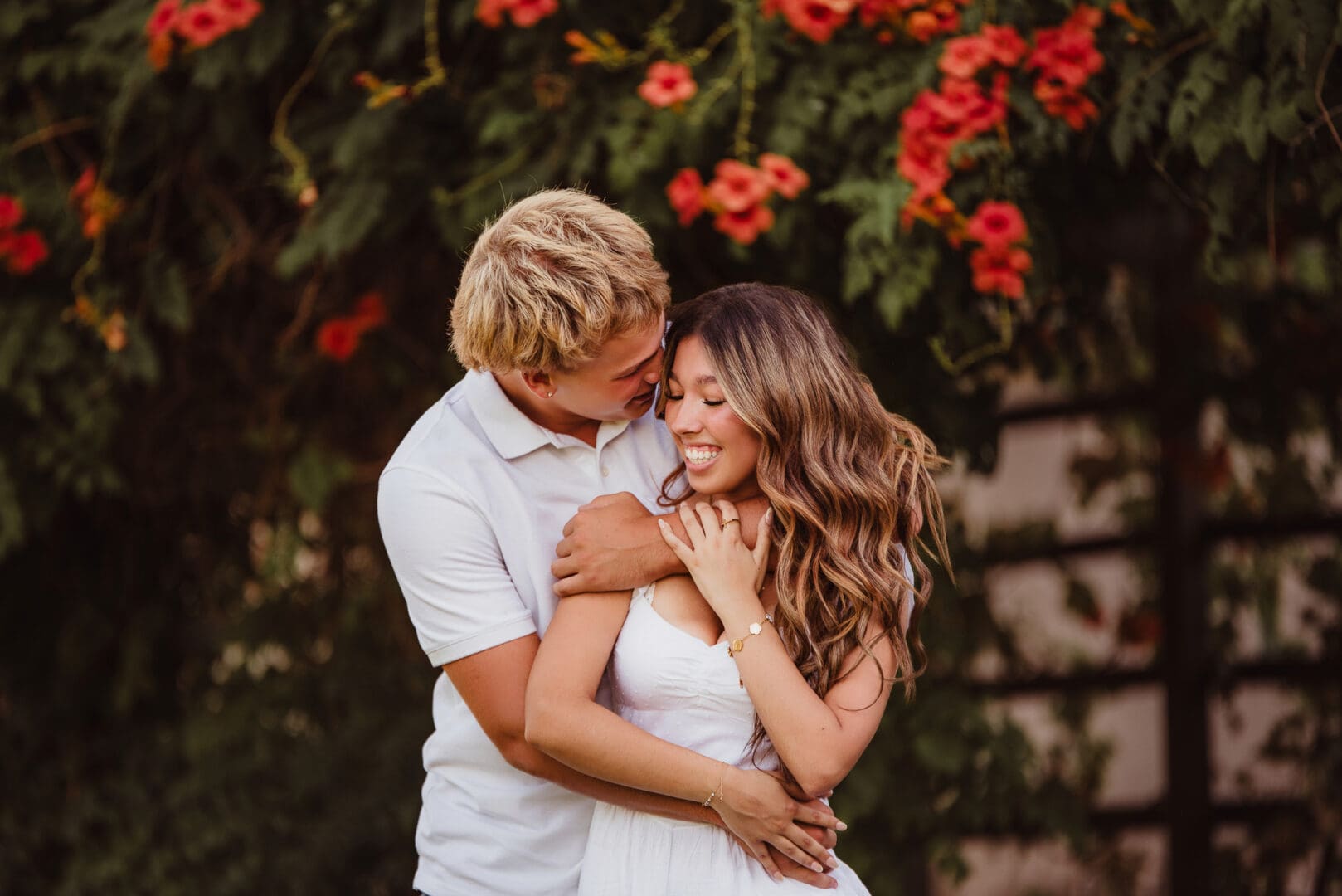 high school sweethearts snuggling in front of hibiscus flowers