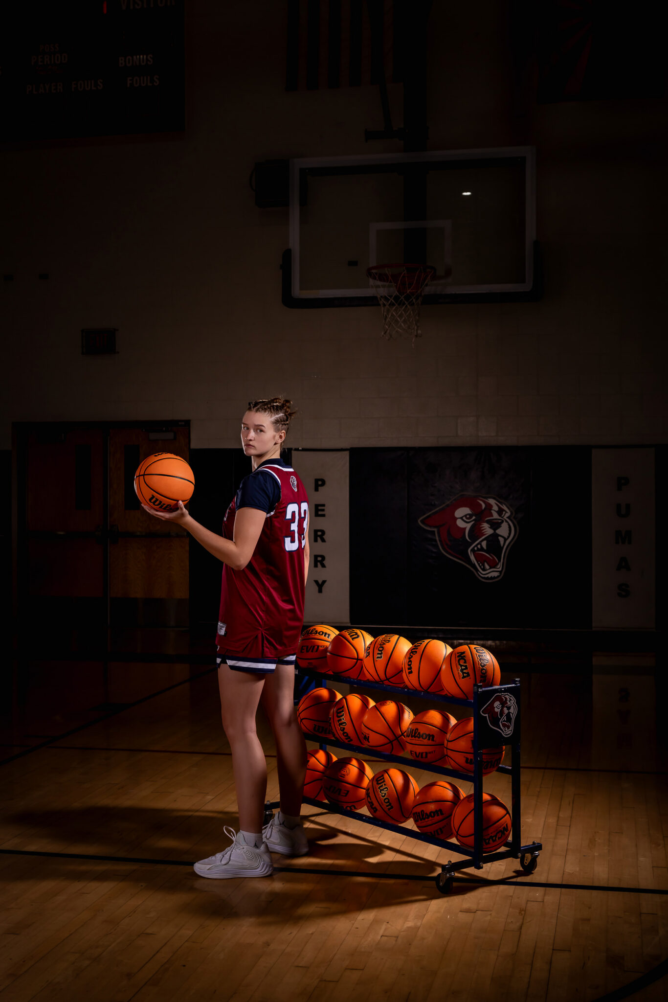 High school basketball player posing with her basketball for senior portraits