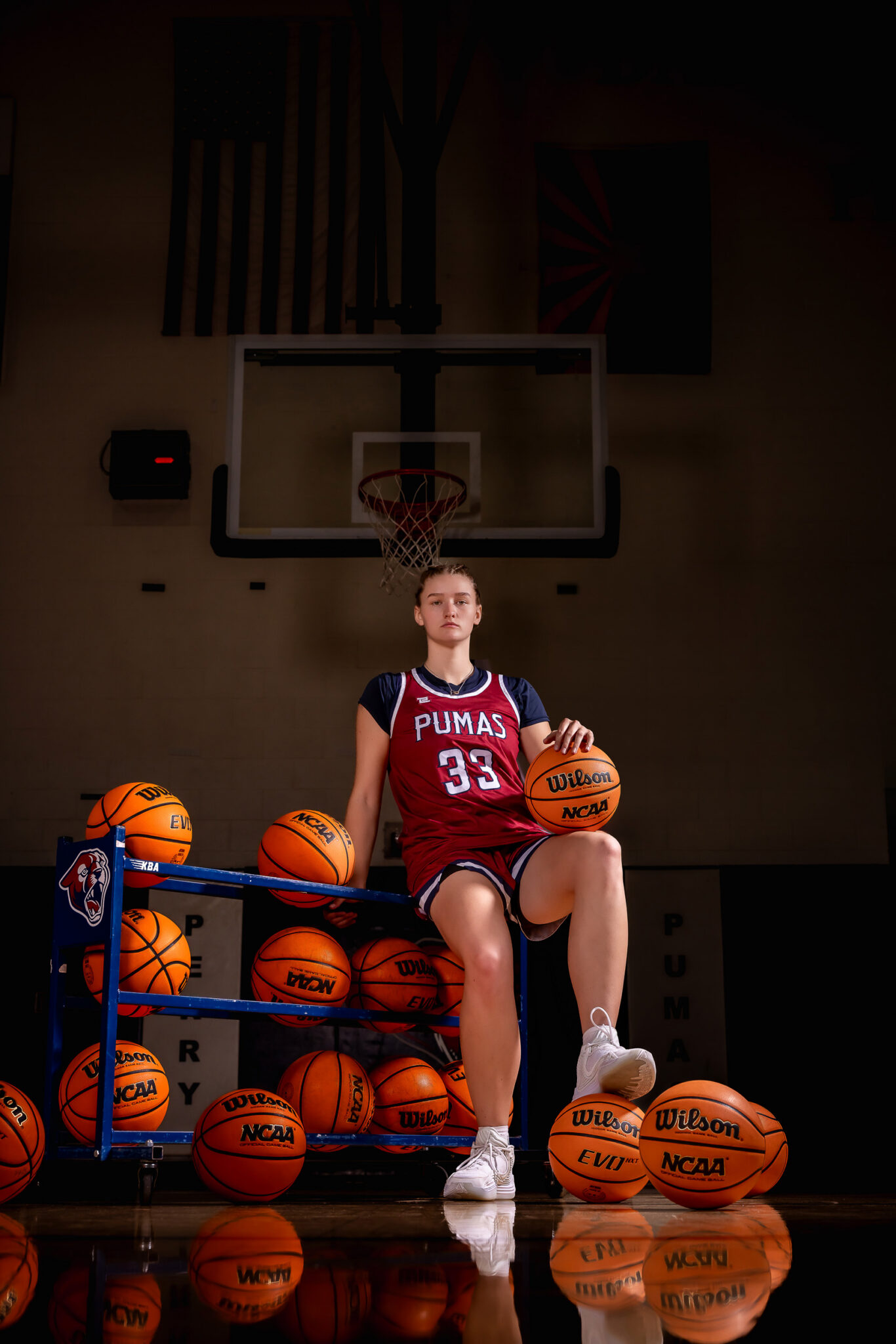 Female athlete senior portrait featuring dramatic lighting inside the gym