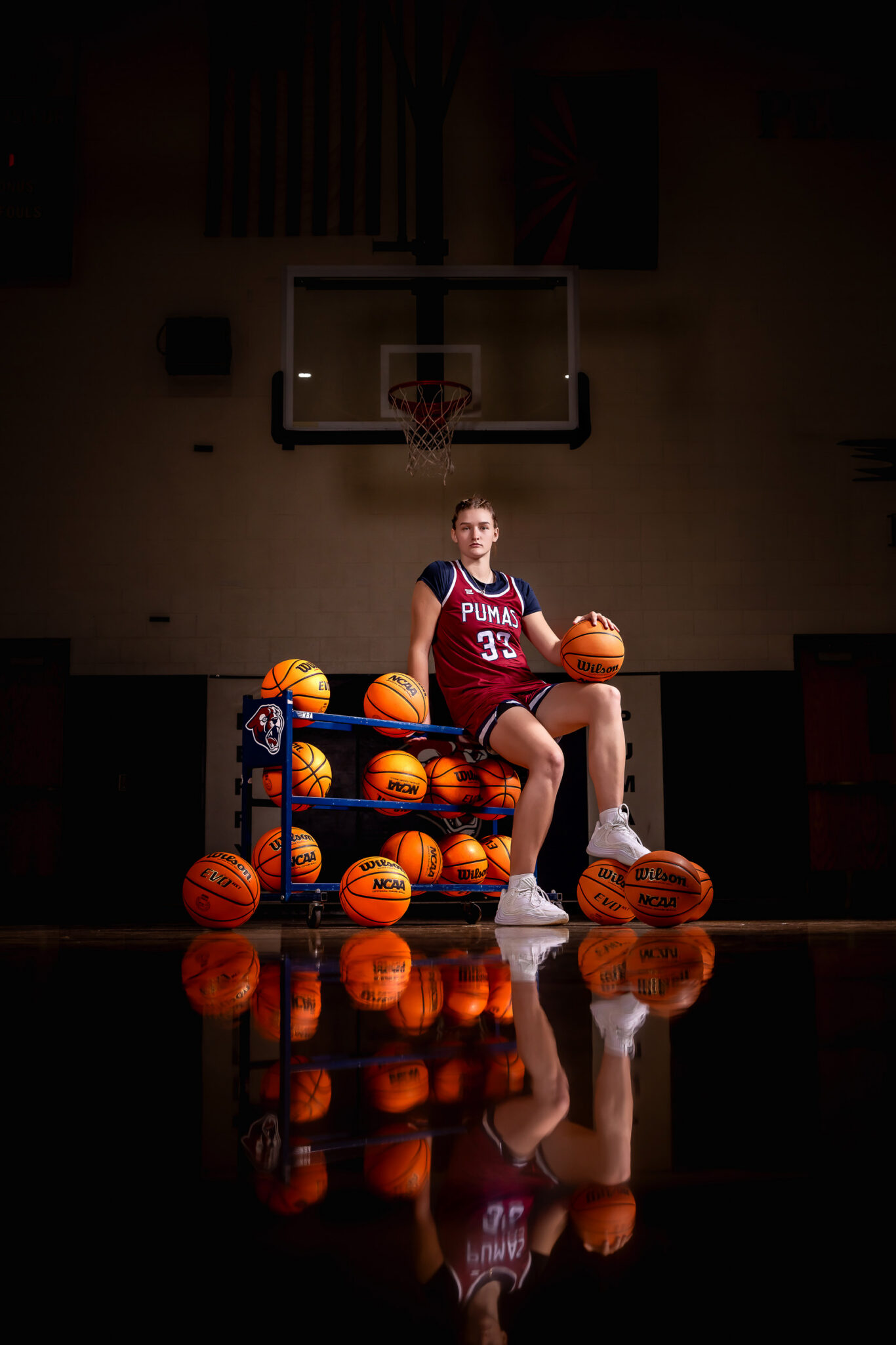 girl basketball player sitting on basketball cart with dramatic sports lighting